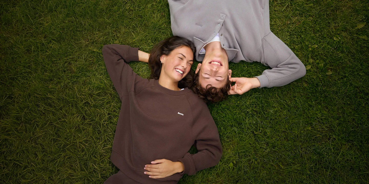 Two friends in soft fall layers, lying together on green grass